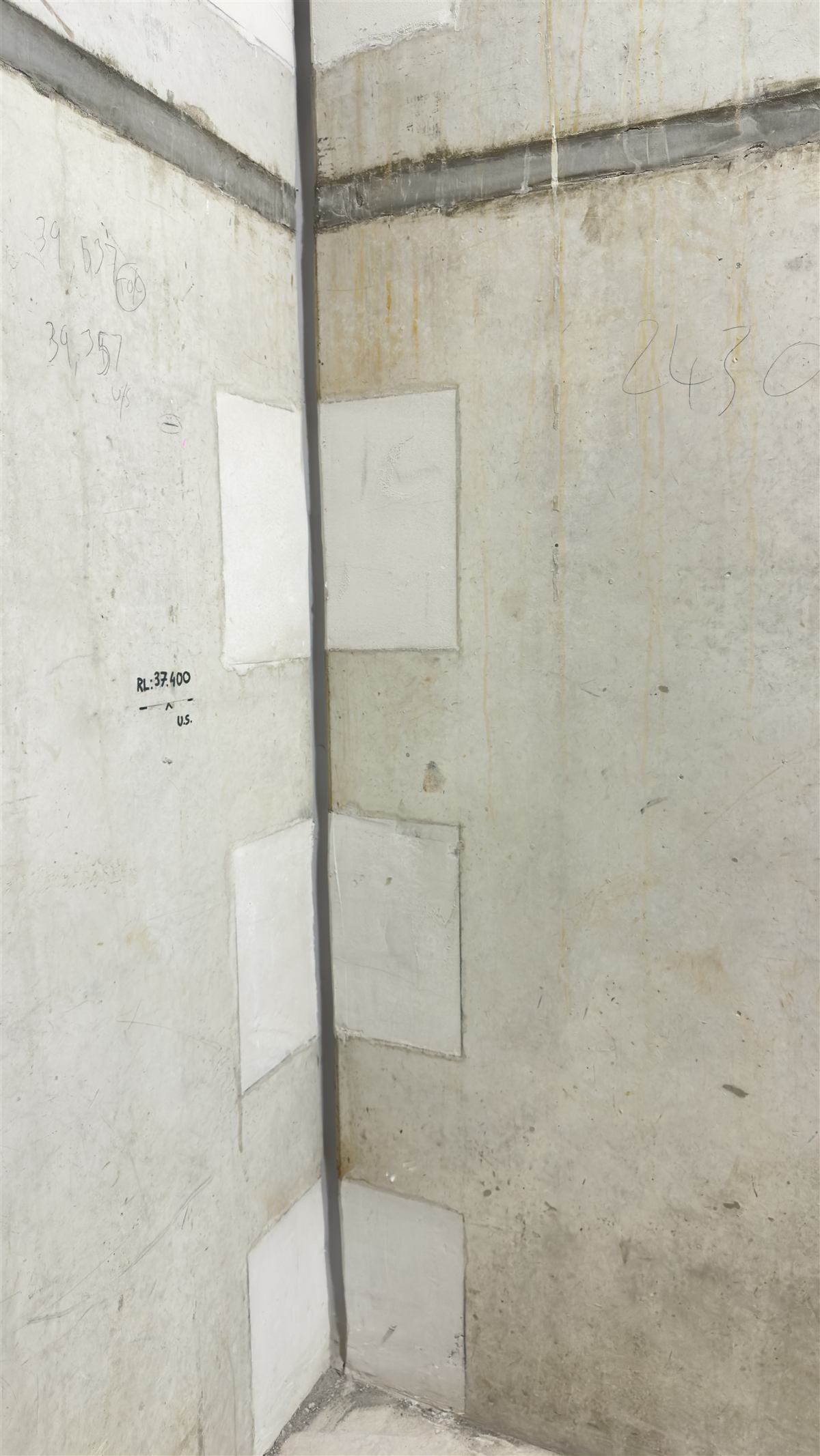 Patched wall penetrations and sealed corner joint in a concrete stairwell