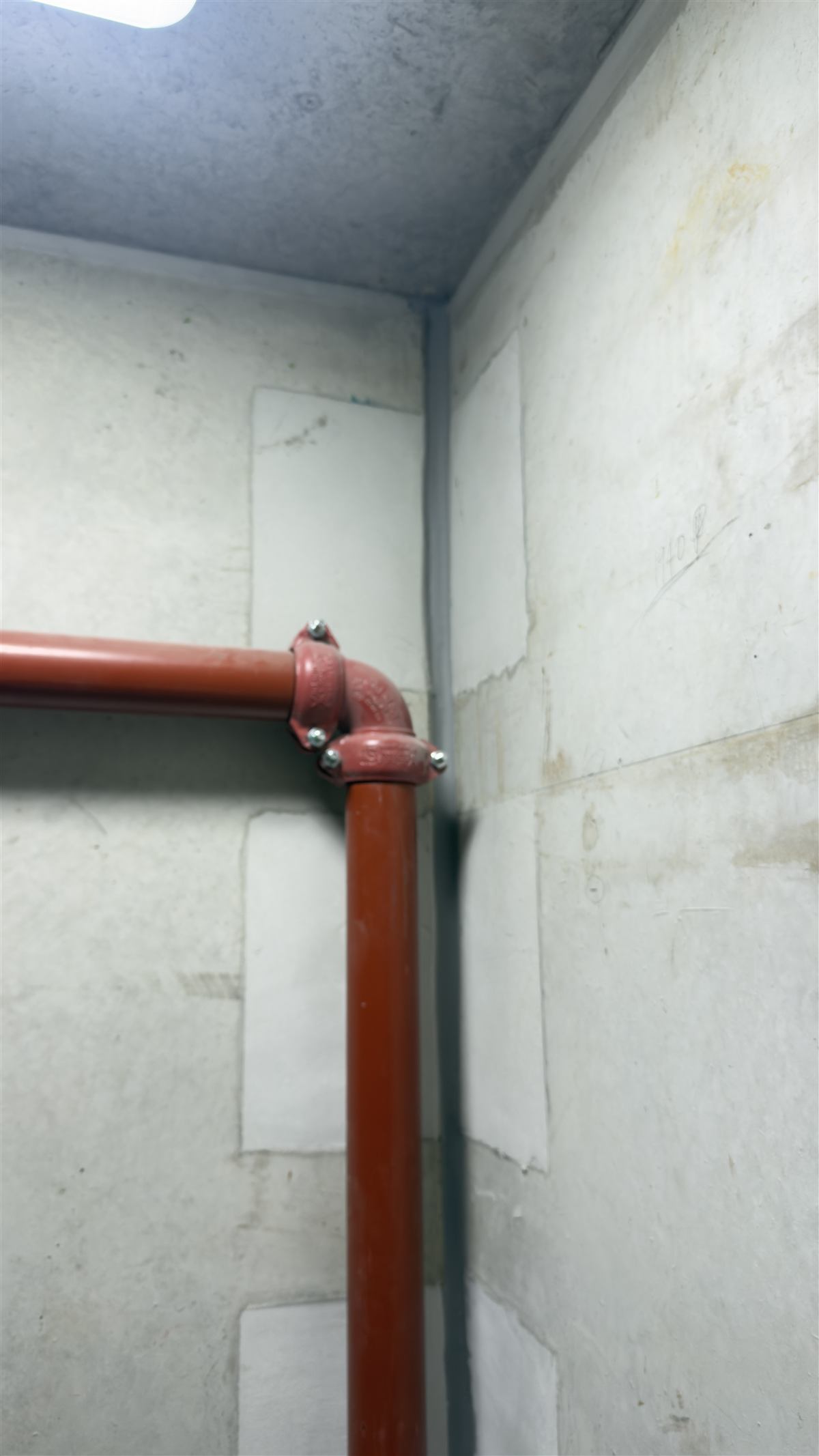 Caulked corner joint in a services riser with fire pipework